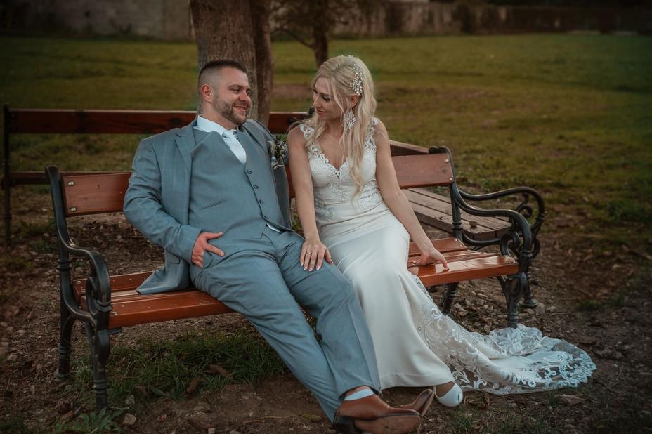 Fotograf foti ako zenich s nevestou sedia na lavicke